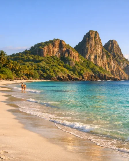 Destinos Naturais da Bahia Que Surpreendem: Praias, Cachoeiras e Trilhas Praia paradisíaca da Bahia com areia branca, águas azul esverdeado e formação rochosa ao fundo, turistas caminhando na orla e vegetação exuberante ao redor